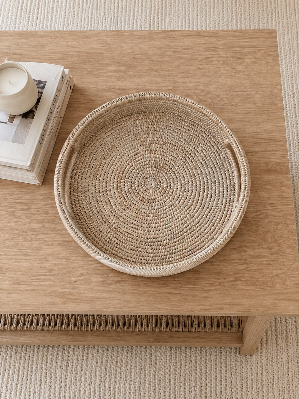 Alden rattan tray on a wooden coffee table with books and a candle