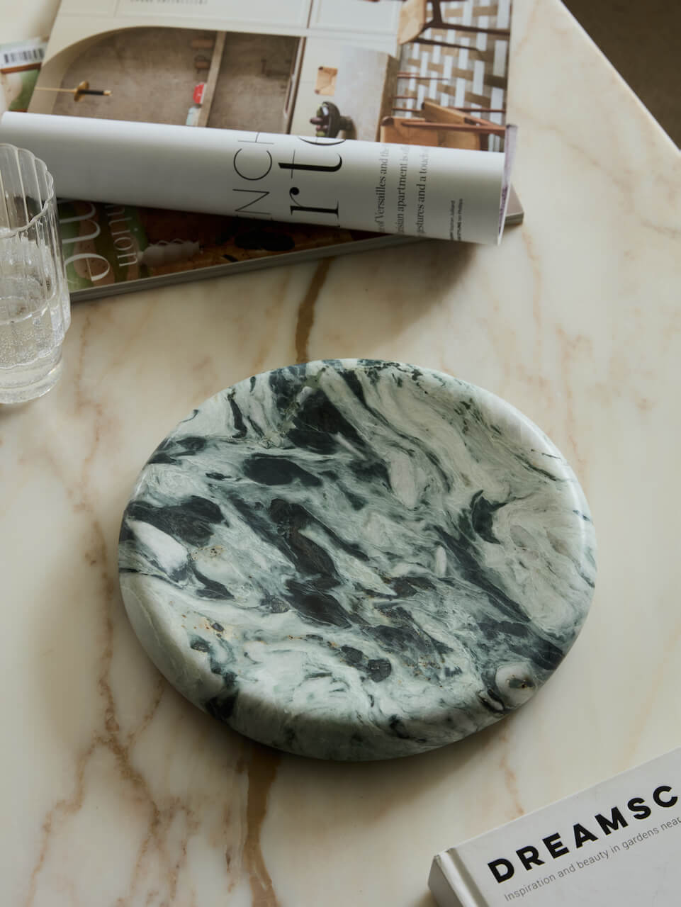 Marble-patterned green marble tray on a marble surface with a magazine and glass in the background