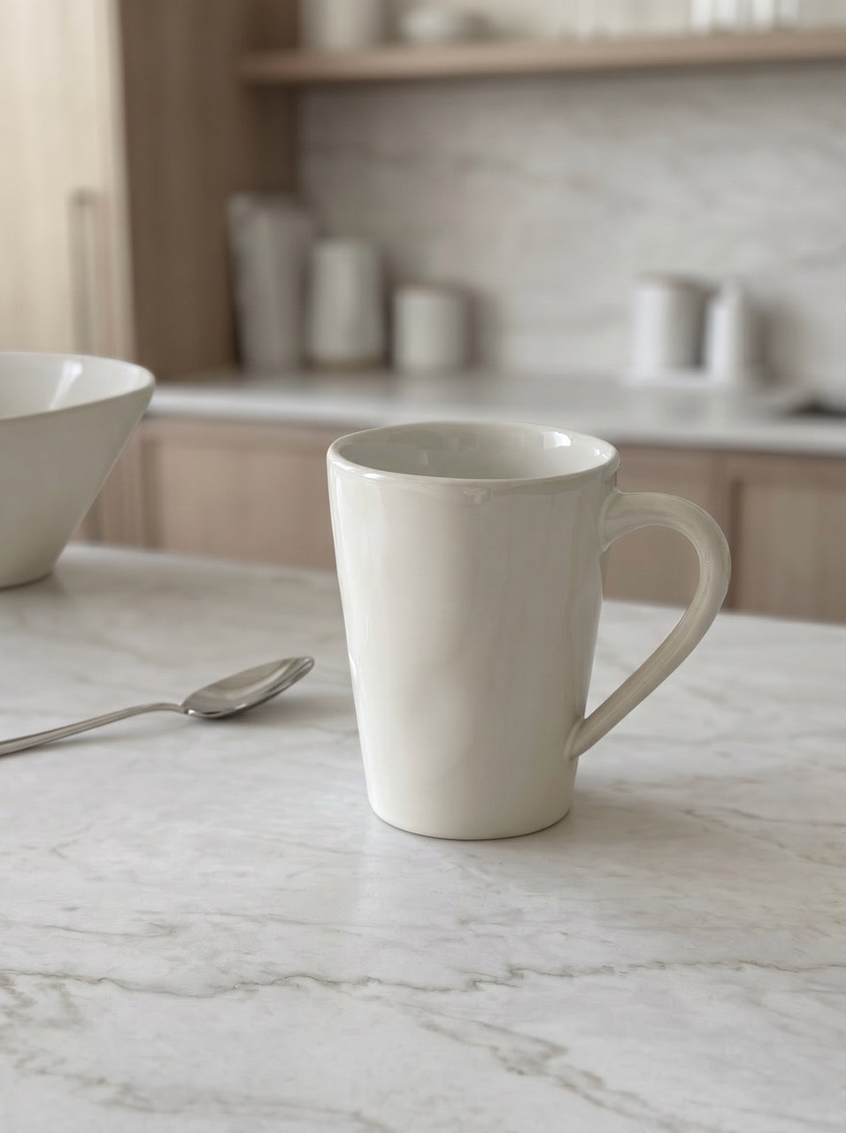 White ceramic mug on a marble countertop with kitchen shelves in the background