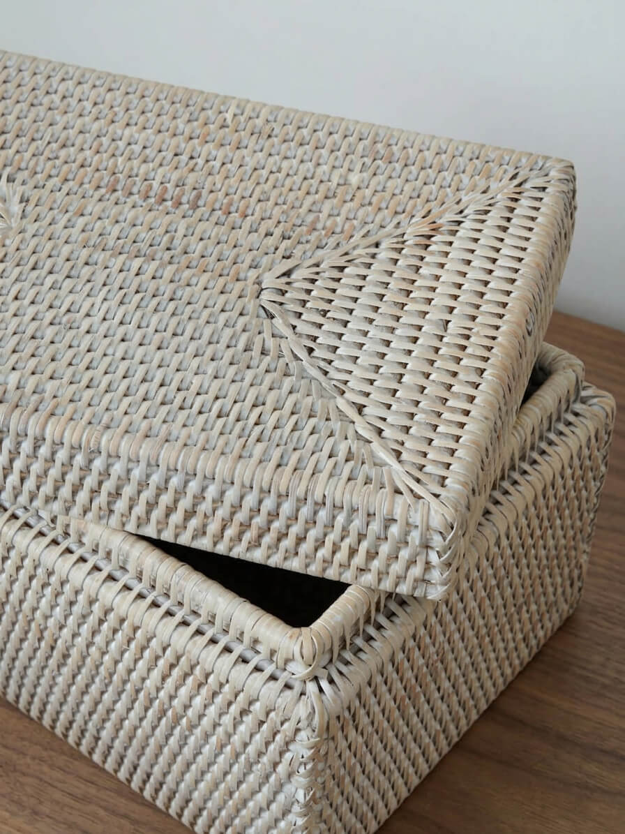 white handwoven rattan storage box with lid slightly open, showing structured weave and interior storage space on wooden surface