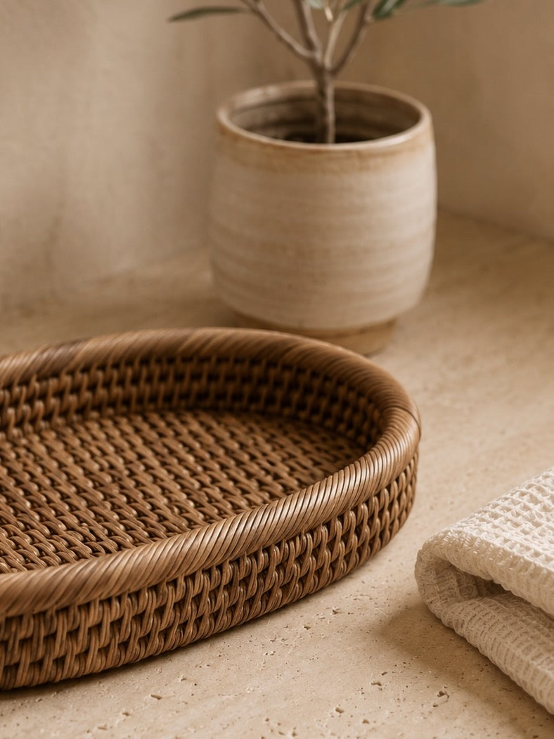 Jarra rattan tray on a beige surface with a plant and folded fabric in the background