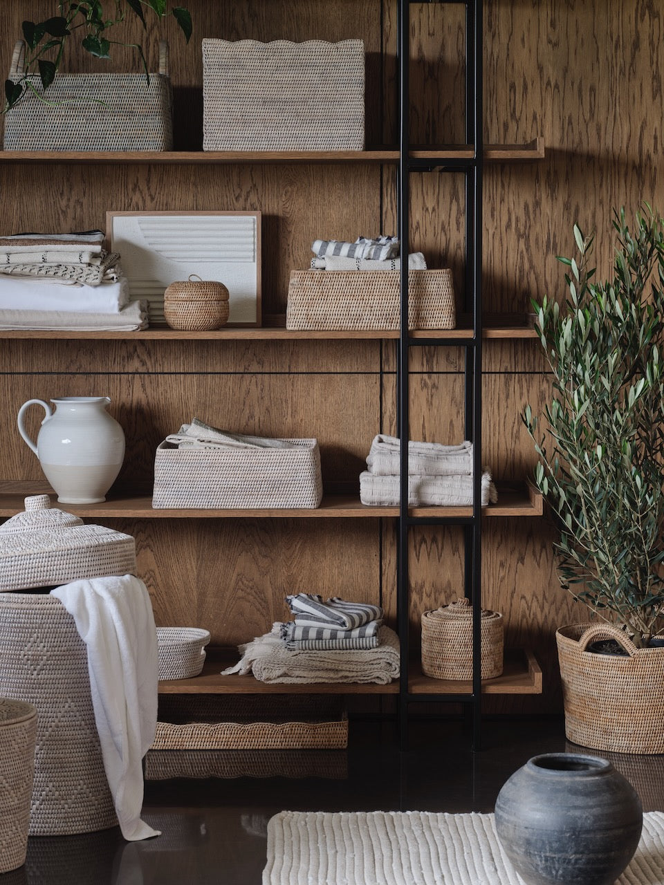 Luxury handwoven rattan storage baskets styled on wooden shelving with neutral linens and home decor, premium natural rattan organisation ideas