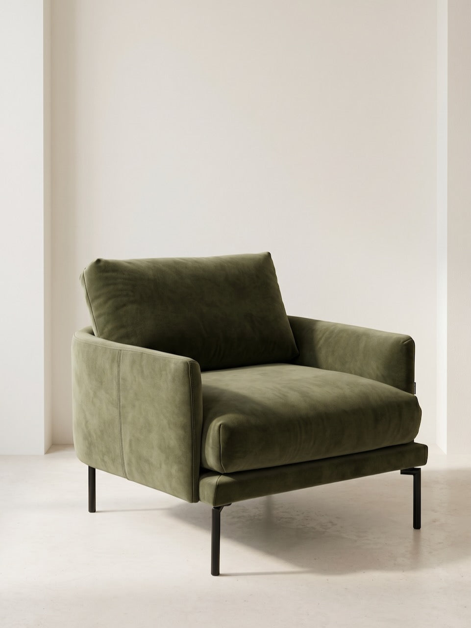 Green armchair in a minimalistic room with white walls and floor.