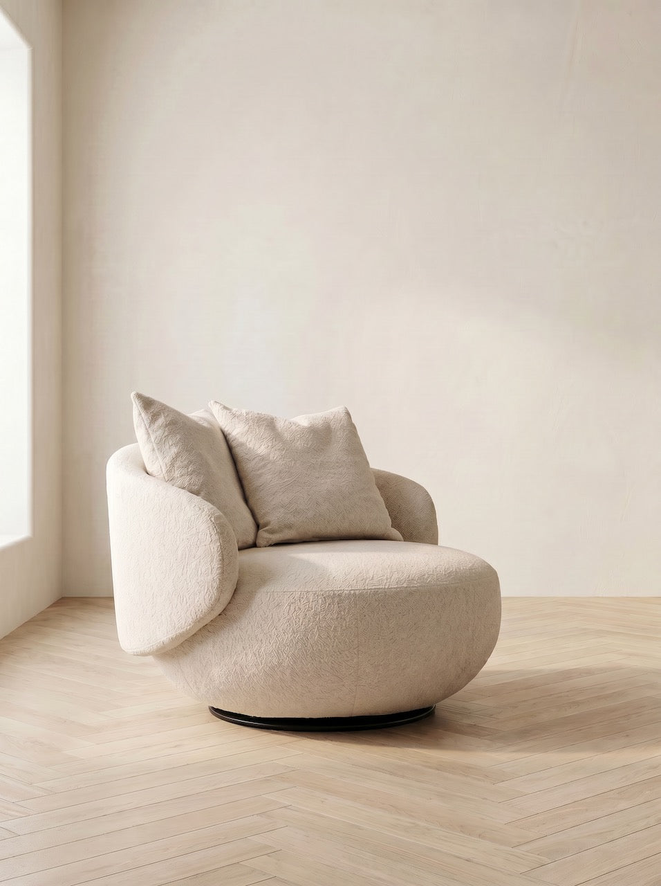 Beige armchair with cushions in a minimalistic room with light wood flooring and white walls.