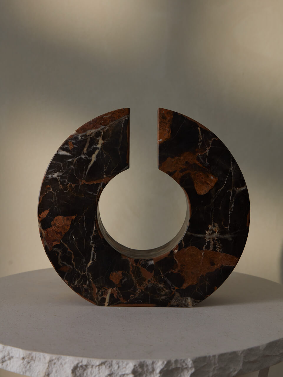 A Portoro marble sculpture with golden tones and dark chocolate background, displayed on a neutral surface.
