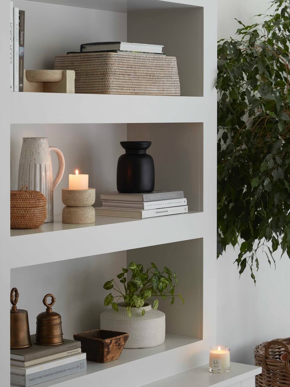 White rattan shelf basket styled on modern shelving with candles, books and ceramics, elegant storage solution for living room or bedroom UK