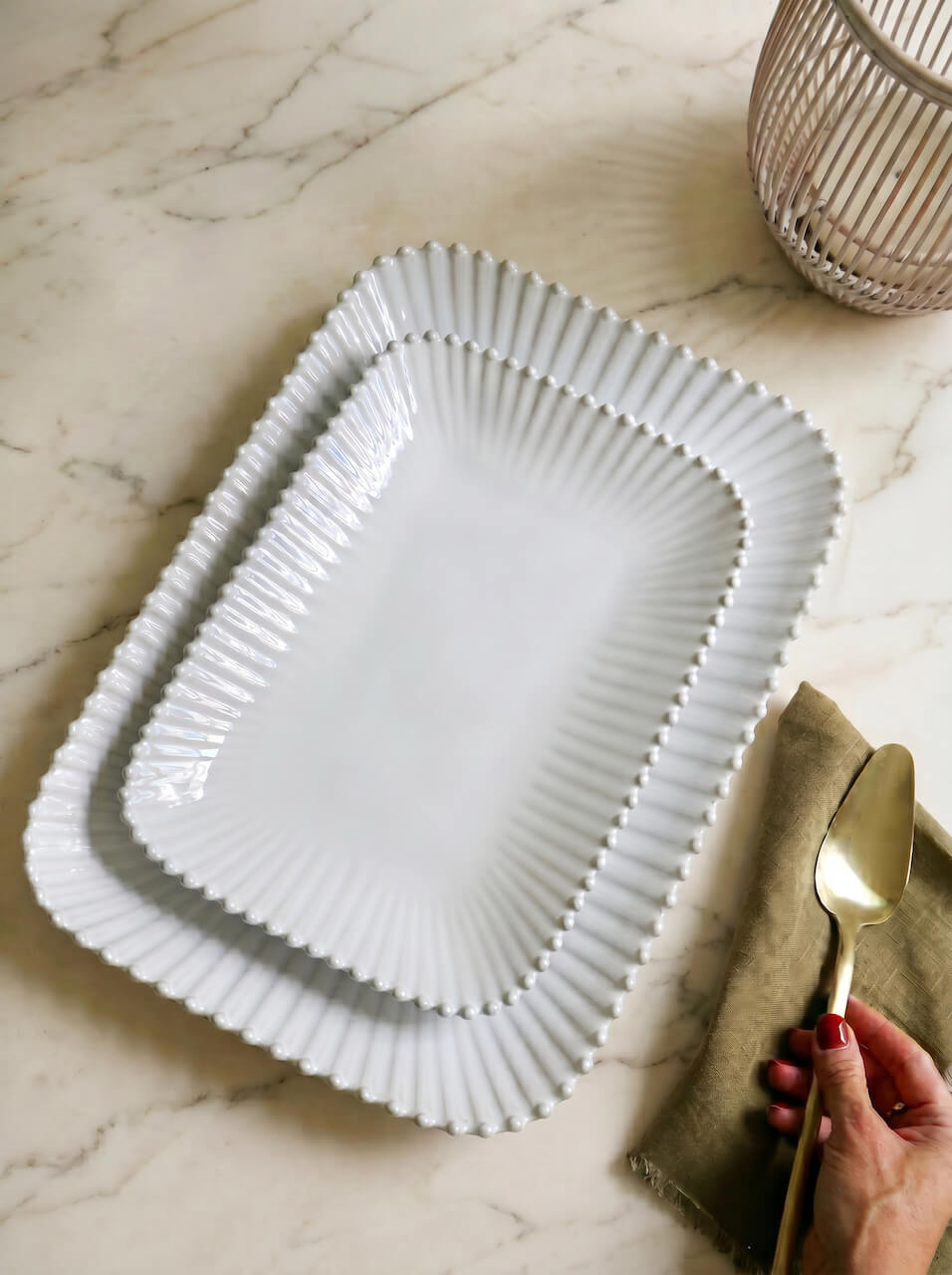 White square glass plate on a marble surface with a hand holding a gold spoon.