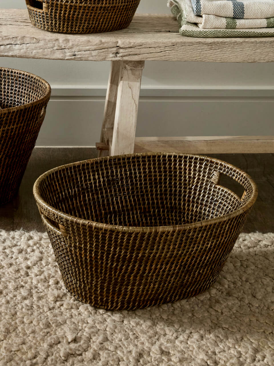 Large Ceres antique brown rattan storage basket on floor with soft rug, woven laundry basket with handles rustic home interior UK