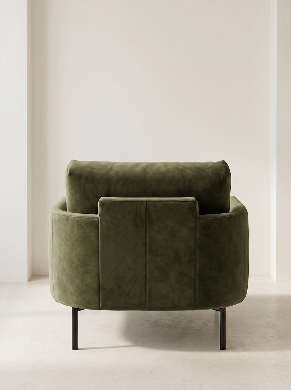Green armchair in a minimalistic room with white walls and floor.