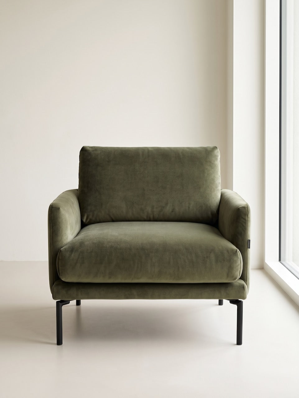 Green armchair in a minimalistic room with a large window.